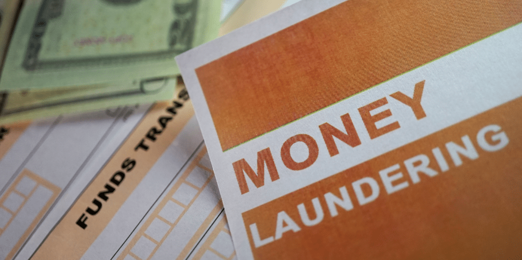 Close-up of "Money Laundering" text on a document near cash and funds transfer forms.
