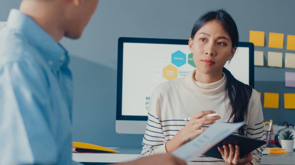 Woman discussing AML/CTF due diligence with colleague in an office