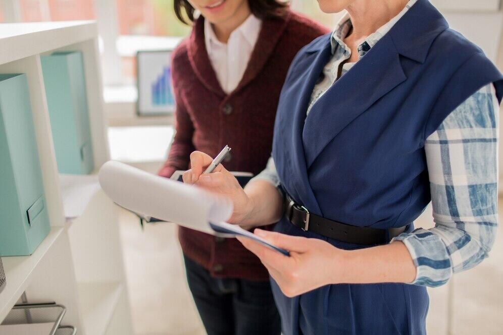 Two businesswomen reviewing documents, discussing Australian AML/CTF compliance.